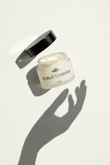 Skincare jar labeled 'Retinol Moisturizer' with open lid on a light background