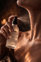 Person applying Cherry Musk body mist to their neck with a warm, brown background.