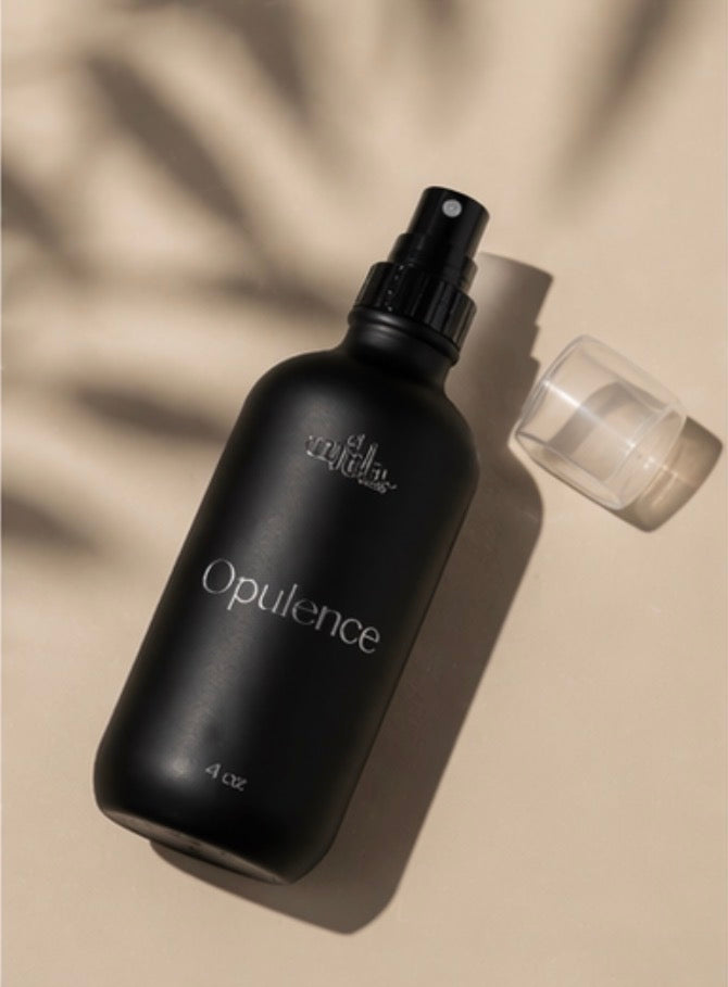 Black 'Opulence' bottle with spray top on a beige background