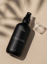 Black 'Opulence' bottle with spray top on a beige background