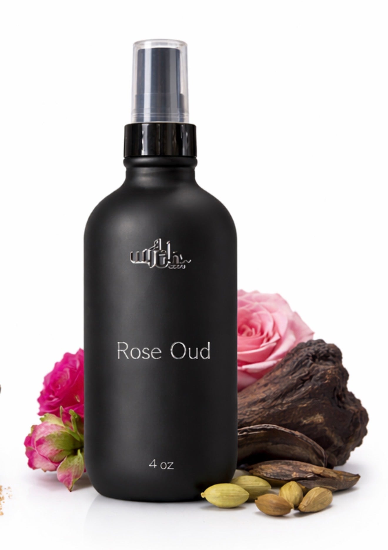 Black bottle of 'Rose Oud' with pink flowers and cardamom pods on a white background
