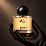 Black satin-gloved hand holding WRTH Opulence Eau de Parfum against a dark, warmly lit background
