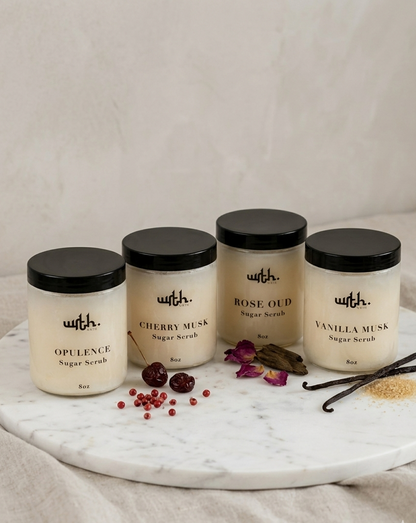 Four jars of 'with.' body scrubs on a marble tray with decorative elements.