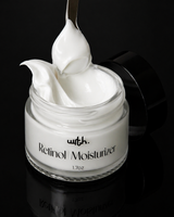 Jar of retinol moisturizer with a spoonful of cream on a black background