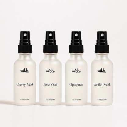 Four white spray bottles with black caps on a white background, labeled with different scents.