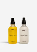 Two bottles of 'Cherry Musk' body mist, one yellow and one white, on a white background.