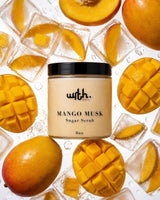 A jar of with. beauty Mango Musk Sugar Scrub is centered, surrounded by fresh mangoes and ice cubes on a white background.