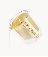 Clear glass beaker pouring warm vanilla musk body elixir candle oil with beige label