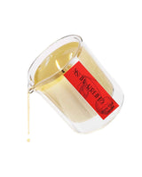 Lit cherry musk body elixir candle in clear glass jar with dripping liquid wax